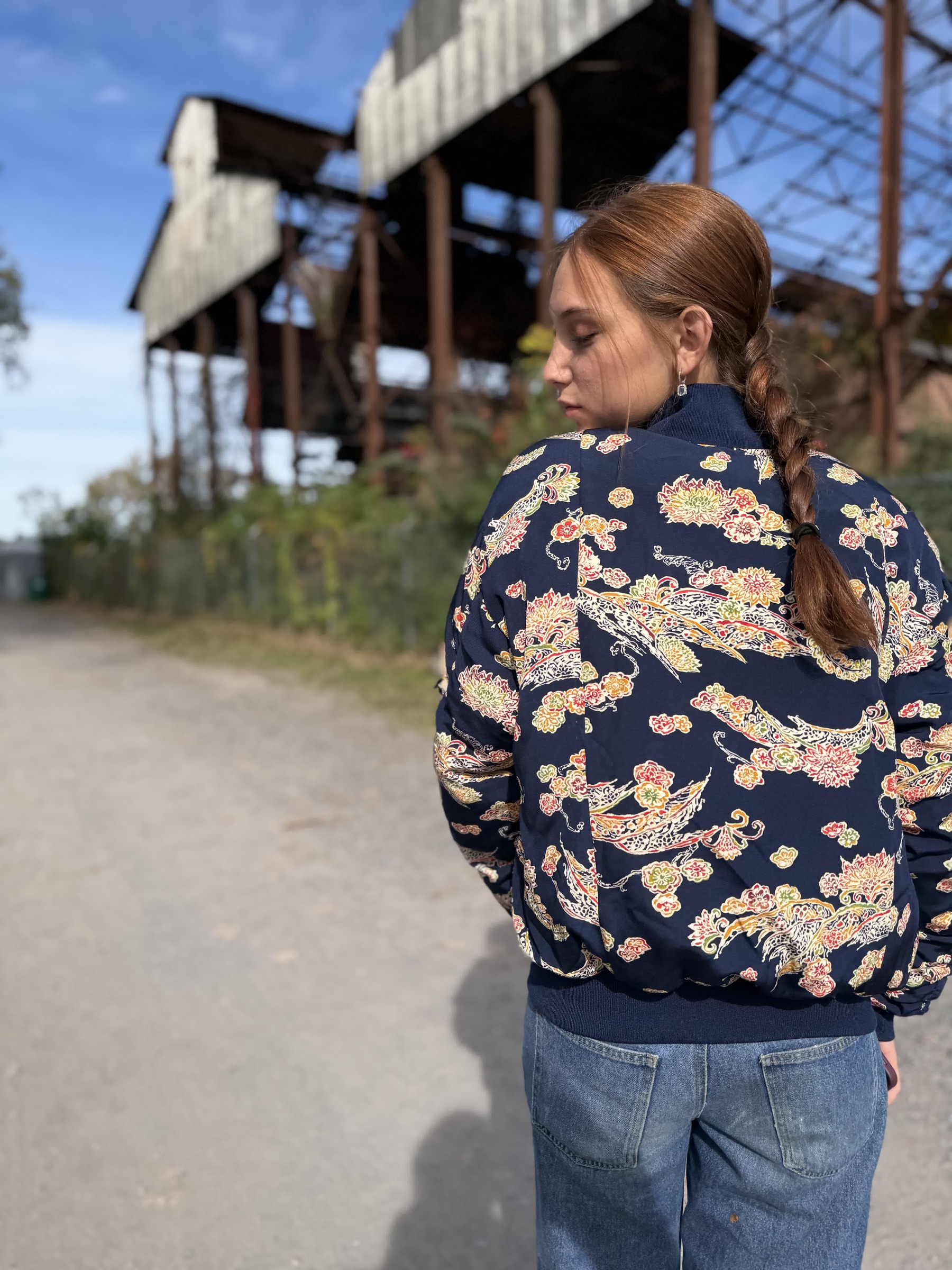 Field + Supplyの会場を背景に、ALISAの柄入りジャケットを着用するモデル